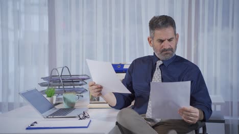 Mature-businessman-looking-at-papers-in-his-office,-looking-at-financial-data,-looking-at-financial-statements.